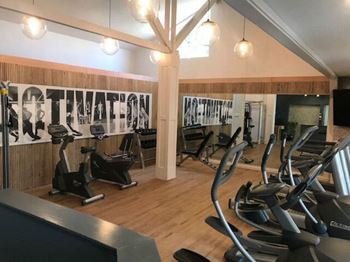 A gym with cardio machines and weights on the floor